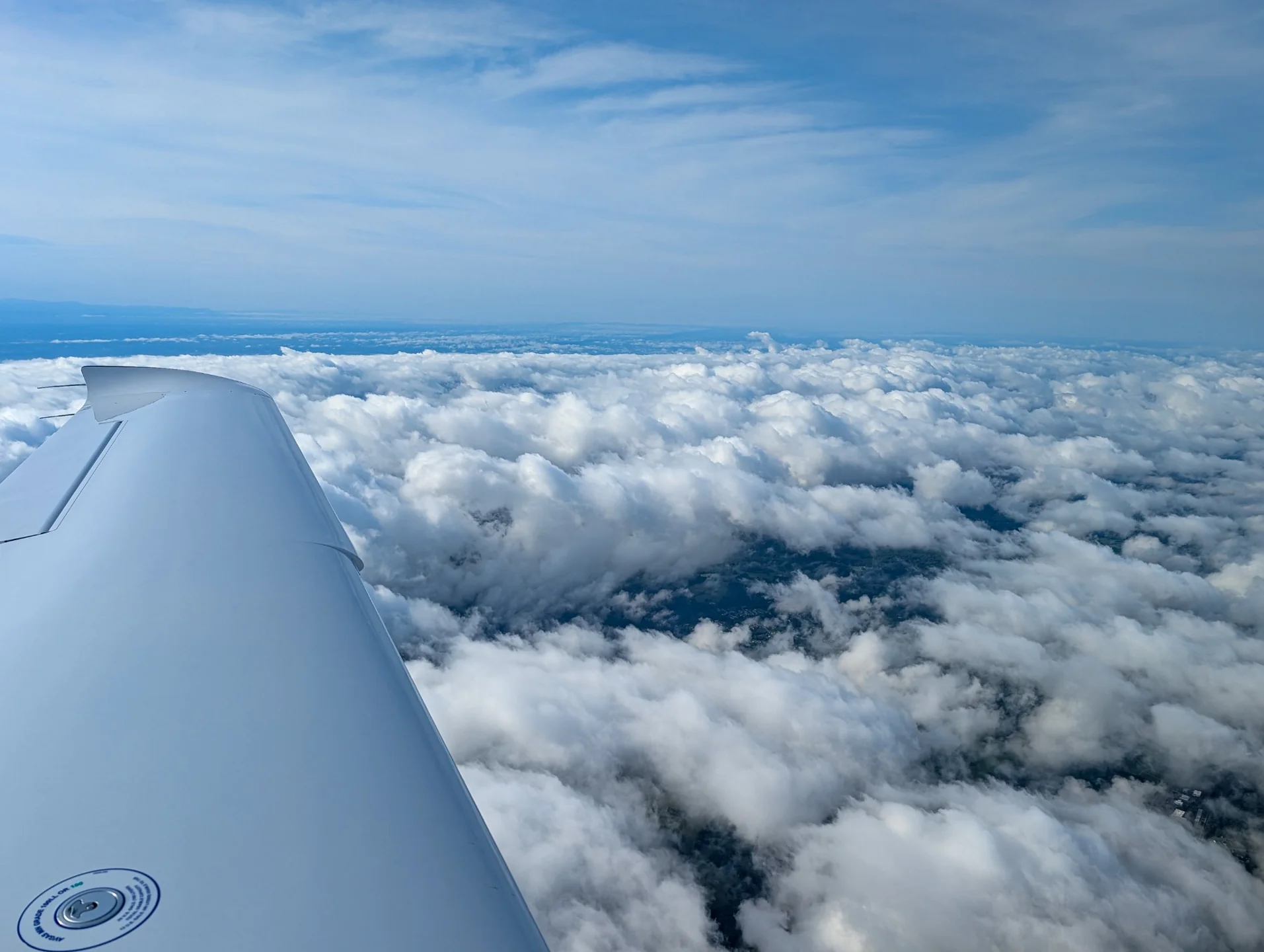 The left wing of N721TP above a layer of white clouds