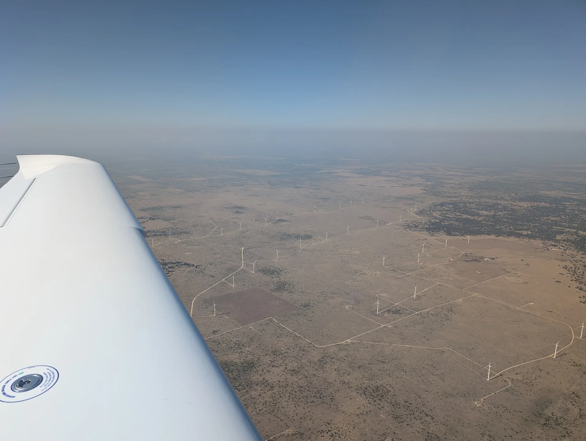The wing above wind turbines in a broad dry landscape